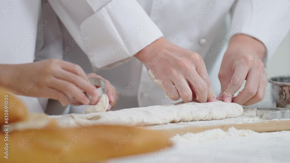 Close up hands of chef cooking or baking together. Press the stainless steel mold onto the dough. to make various shapes. Cooking or baking concept Close up hands of chef cooking or baking together. Press the stainless steel mold onto the dough. to make various shapes. Cooking or baking concept