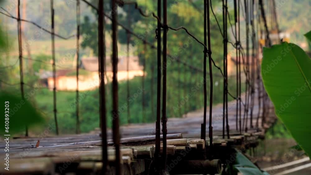 Wooden suspension bridge is swaying after passing the vehicle - Rural view of Indonesian countryside Wooden suspension bridge is swaying after passing the vehicle - Rural view of Indonesian countryside