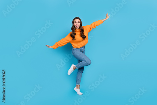 Full length photo of childing fooling woman wear orange sweater having fun arms sides isolated blue color background