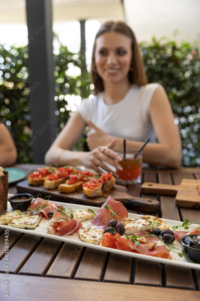 Antipasti and bruschetta served on a wooden table in the restaurant with blurred people in the background