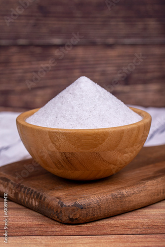 Natural minaret crystal non-iodized grinding salt on wooden background. Ground rock salt in wooden bowl. Close up