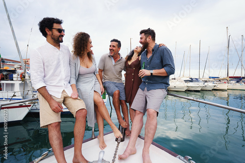 Friends Chatting on Boat Deck - A diverse group of adult friends, engage in a lively conversation on the deck of a boat docked at the harbor. They enjoy each other's company and share laughter © Lomb