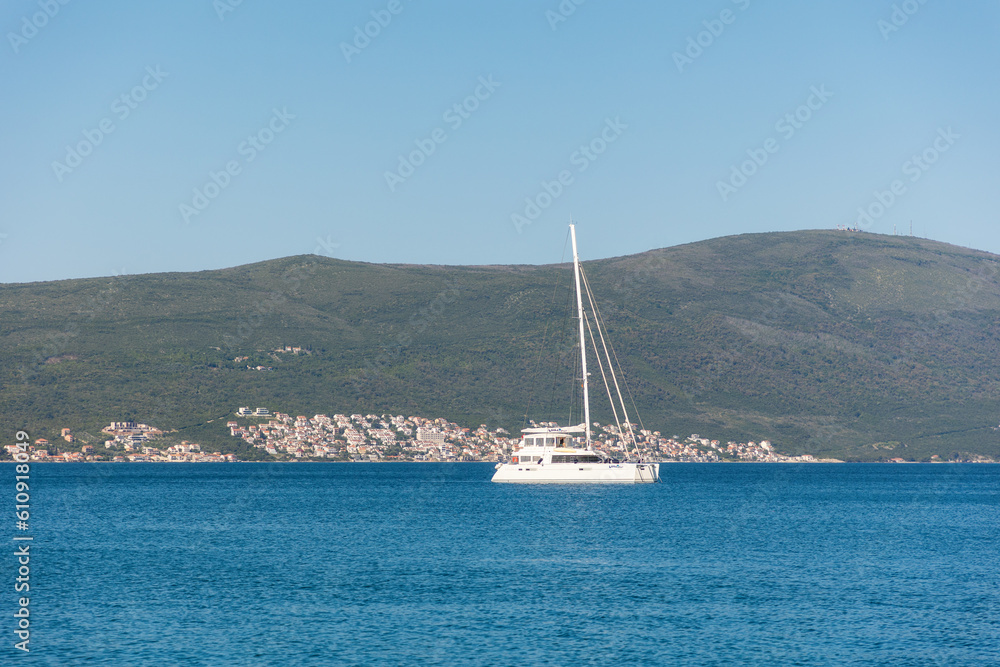 White sailing boat in the blue sea against the background of green mountains. Summer landscape. Copy space White sailing boat in the blue sea against the background of green mountains. Summer landscape. Copy space