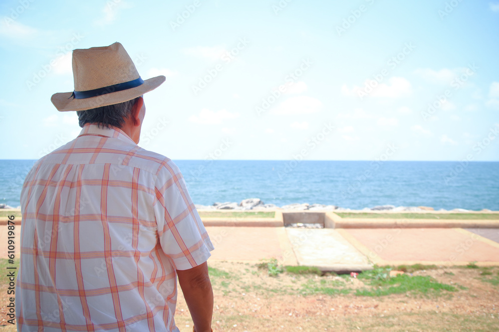 Asian elderly man sitting at the beach. Living in retirement. travel. copy space