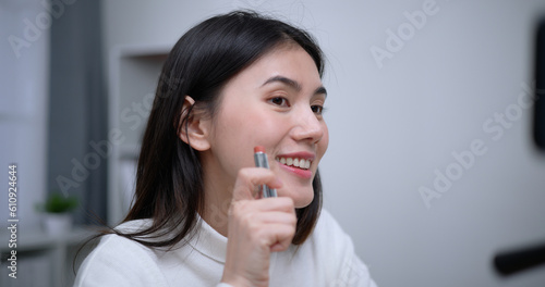 Beautiful young Asian woman blogger shows how to make up cosmetics at home