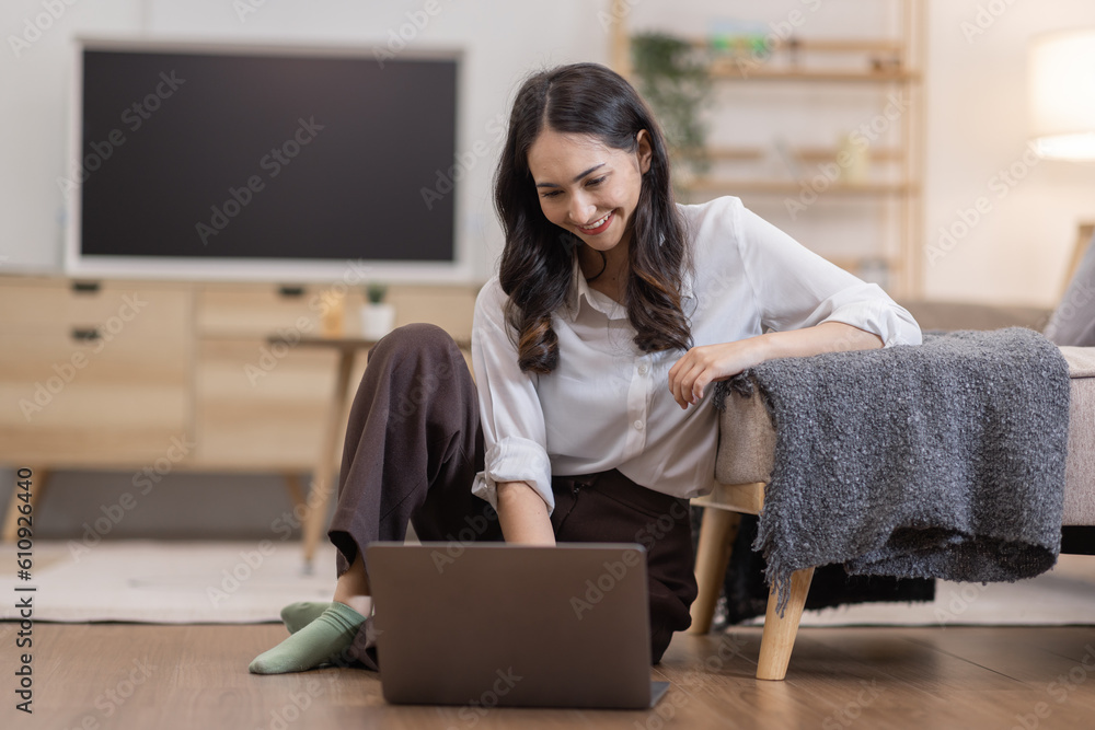 © David - Portrait of a young happy asian female freelancer sitting on the couch and working on project, watching movie on laptop, studying, blogging, resting and chatting online.