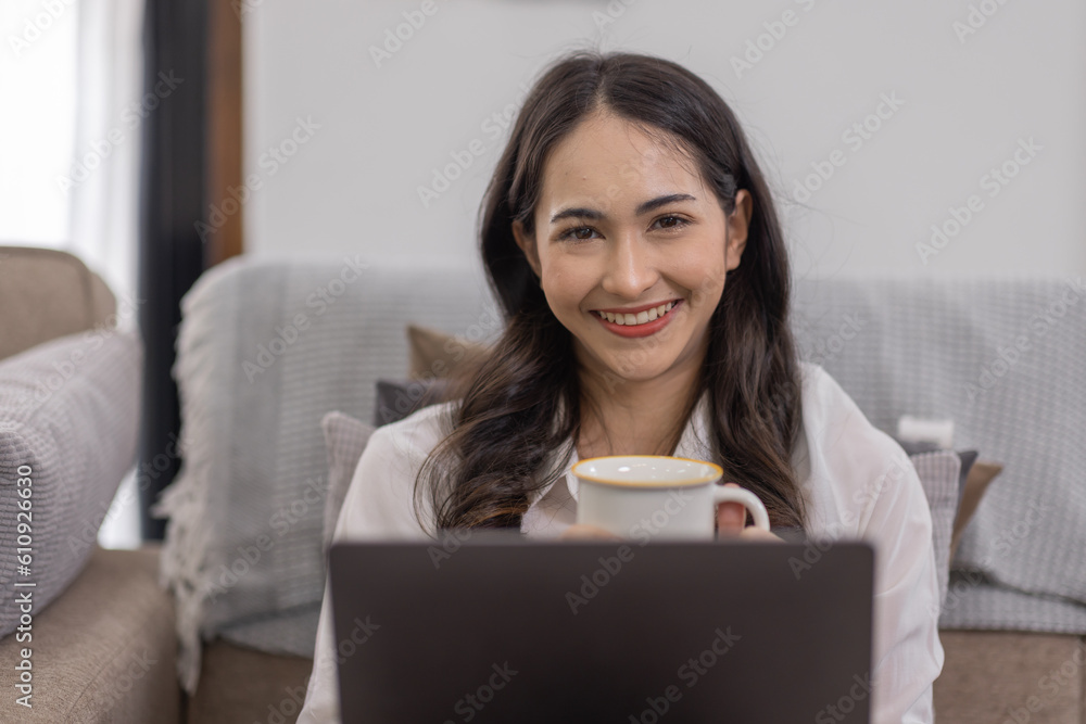 Portrait of a young happy asian female freelancer sitting on the couch and working on project, watching movie on laptop, studying, blogging, resting and chatting online. Portrait of a young happy asian female freelancer sitting on the couch and working on project, watching movie on laptop, studying, blogging, resting and chatting online.
