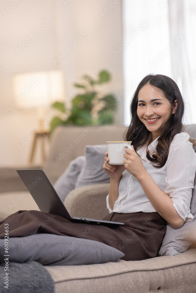 Portrait of a young happy asian female freelancer sitting on the couch and working on project, watching movie on laptop, studying, blogging, resting and chatting online. Portrait of a young happy asian female freelancer sitting on the couch and working on project, watching movie on laptop, studying, blogging, resting and chatting online.