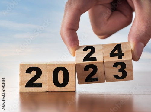 New Year concept from 2023 to 2024. Man's hand change wooden cubes on white table. Change, success and new business plans concept