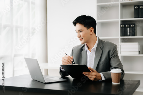 Young business man working at office with laptop, tablet and taking notes on the paper..
