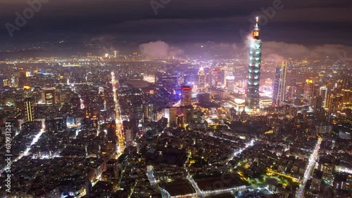 Aerial hyperlapse of Taipei, the vibrant capital of Taiwan, on a foggy evening, with 101 Tower standing out in Xinyi District, city lights dazzling in the dark and low clouds flowing among skyscrapers