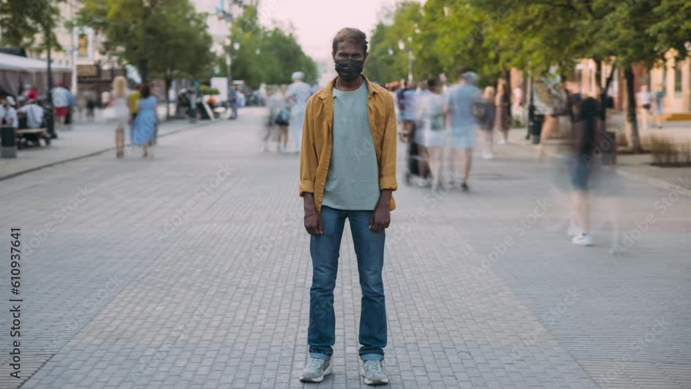 Time lapse portrait of young Indian man in medical masj standing in city center during covid-19 outbreak. Pandemic and youth concept. Time lapse portrait of young Indian man in medical masj standing in city center during covid-19 outbreak. Pandemic and youth concept.