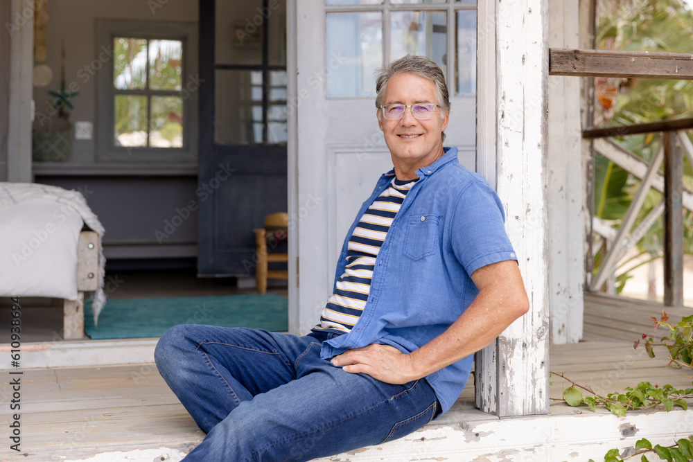 Portrait of smiling caucasian senior man sitting on steps outside wooden cottage Portrait of smiling caucasian senior man sitting on steps outside wooden cottage