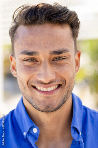 Close-up portrait of handsome caucasian young man with brown eyes smiling and looking at camera
