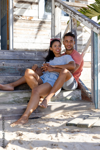 Smiling caucasian young couple looking away while sitting on staircase outside cottage