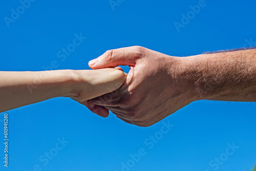 children's and man's hand hold each other against the blue sky. Help the girl. Social care for children © Nataliia Makarovska