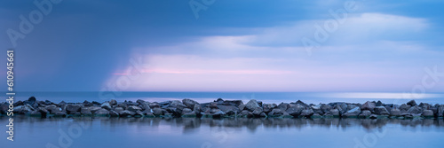 Breakwater built of stones. Long exposure photo. The Baltic Sea just before the storm.