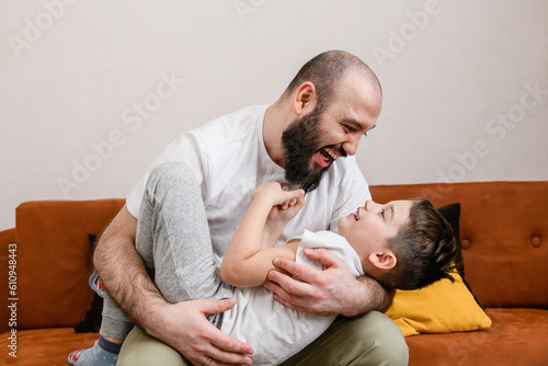 Father hug little boy at home sofa