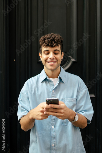 Foto Young man with curly hair using smartphone