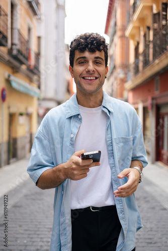 Young man with curly hair using smartphone
