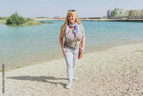Portrait attractive middle-aged woman of plump forms on shore sea or lake photo
