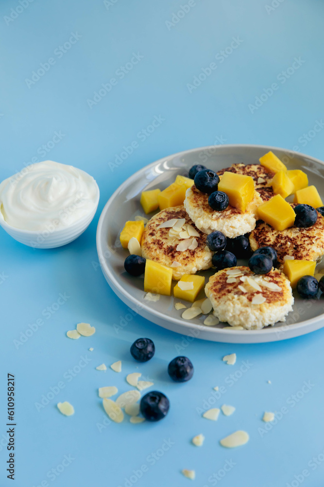 Breakfast with cheesecakes and berries on blue background Breakfast with cheesecakes and berries on blue background