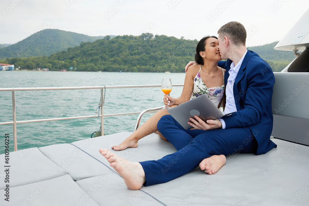 businessman using laptop computer and kissing with girlfriend on luxury yacht businessman using laptop computer and kissing with girlfriend on luxury yacht