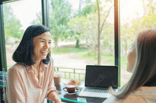 Female studying the local coffee shop. Two women discussing business projects in a cafe while having coffee. Startup, ideas and brain storm concept. Smiling friends with hot drink using laptop in cafe
