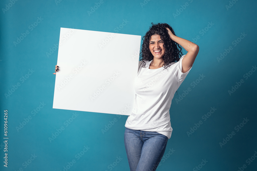 Beautiful curly woman holding blank billboard isolated on blue background Beautiful curly woman holding blank billboard isolated on blue background