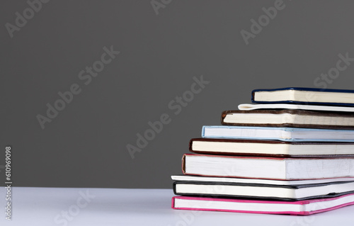 Close up of stack of books and notebooks with copy space on grey background