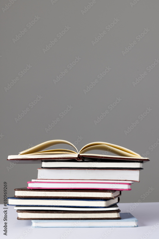 Fototapeta premium Close up of stack of books and notebooks with copy space on grey background