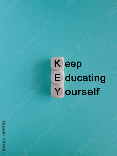 KEY, keep educating yourself symbol. Wooden cubes with words 'KEY, keep educating yourself'. Beautiful blue background, copy space. Business, educational and KEY, keep educating yourself concept.