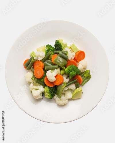boiled, steamed vegetables on a white plate, top view