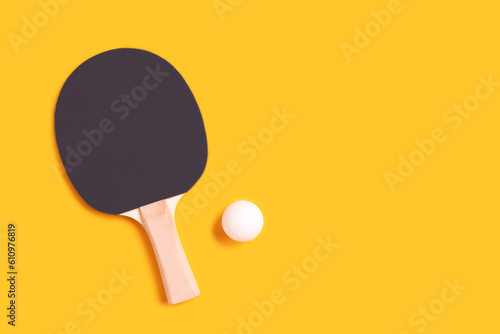 Tennis racket and white ball on a yellow background. Lifestyle concept with copy space.