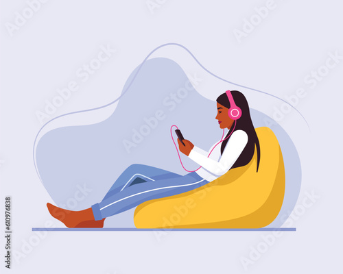 dark-skinned girl with long hair sits on a bean bag chair with a headphones