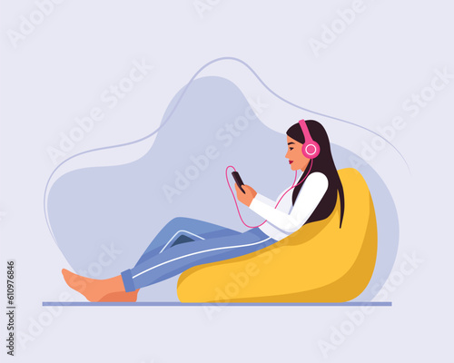 light-skinned girl with long hair sits on a bean bag chair with a headphones	
