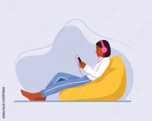 dark-skinned girl with short hair sits on a bean bag chair with a headphones