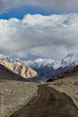 Journey to the Peaks: Barren Valley Road Winds Towards Snowcapped Mountains in Ladakh