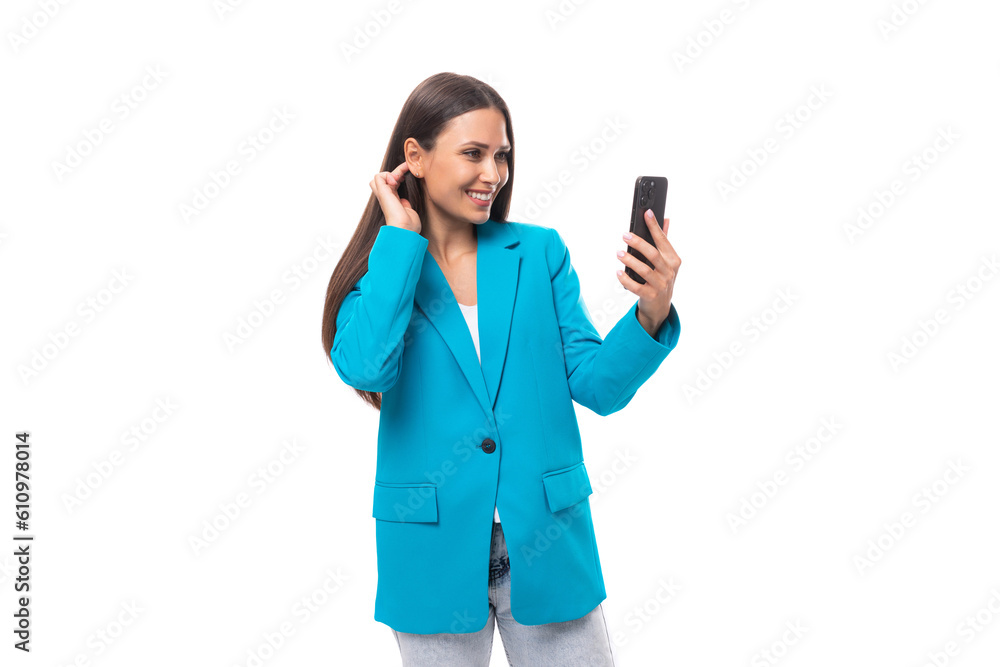 modern stylish young brunette businesswoman in a blue jacket conducts a video call on a smartphone on a white background with copy space modern stylish young brunette businesswoman in a blue jacket conducts a video call on a smartphone on a white background with copy space