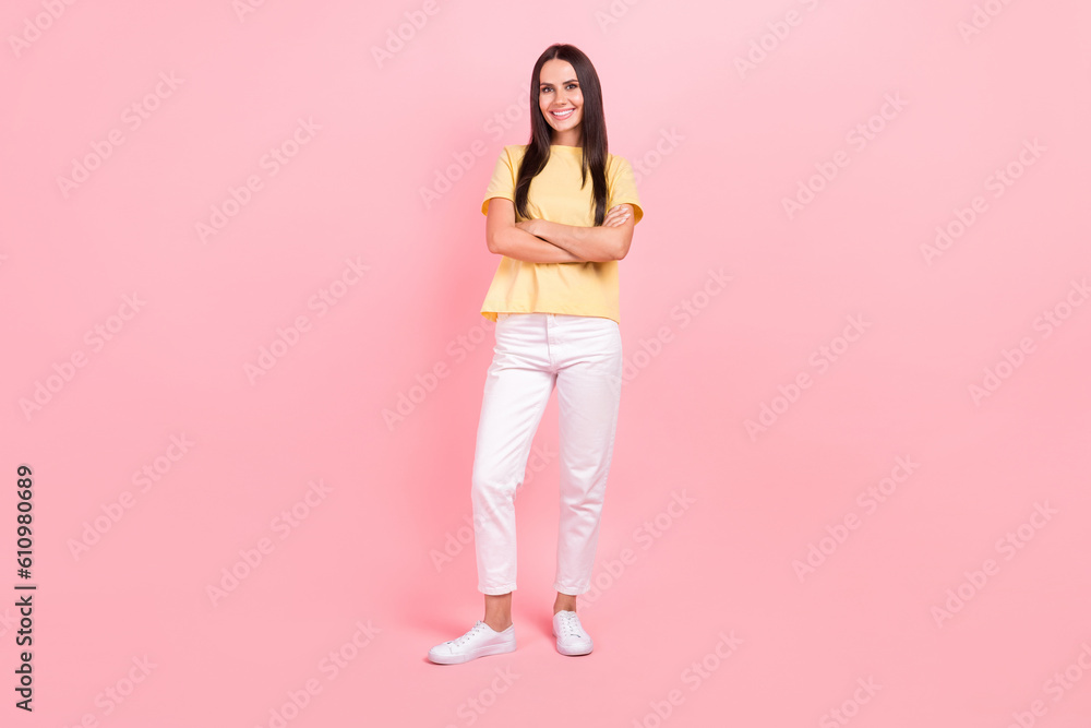 Full length photo of confident cool woman dressed yellow t-shirt smiling arms crossed isolated pink color background Full length photo of confident cool woman dressed yellow t-shirt smiling arms crossed isolated pink color background