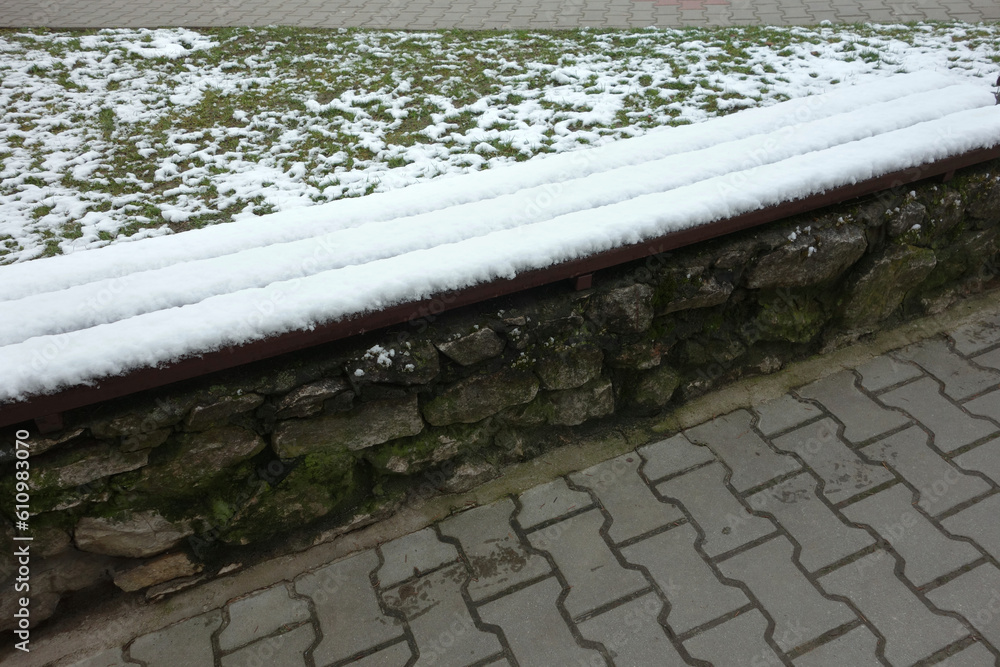 Fototapeta premium Concrete wooden bench covered with snow