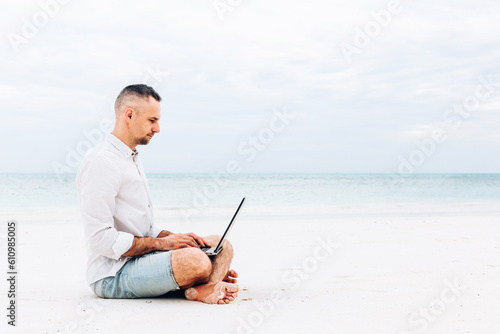 Man hands typing text on laptop computer in front blue sea on thw beach. Concept remote work, freelance. © olyphotostories