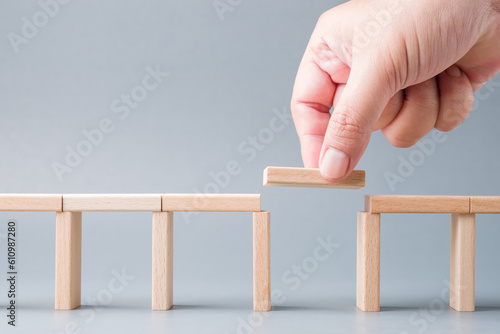 Canvastavla Closeup hand fill a final piece of wood between the gap of a toy bridge, solutio