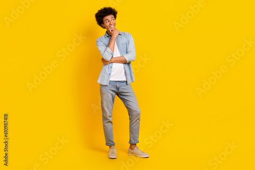 Full length photo of minded positive man arm touch chin look empty space isolated on yellow color background