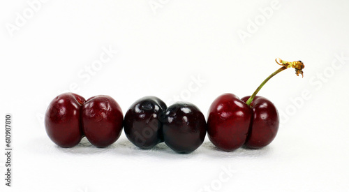 Unusually shaped cherries, fused by two berries isolated on white. Ripe juicy sweet burgundy cherry close-up.