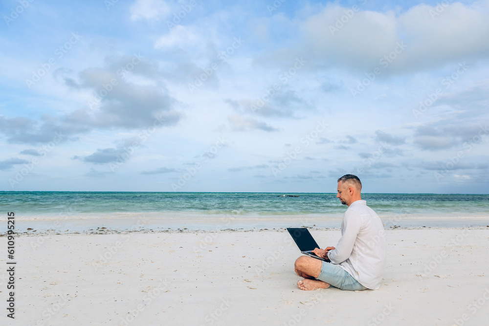 man with laptop on colorful beach of island