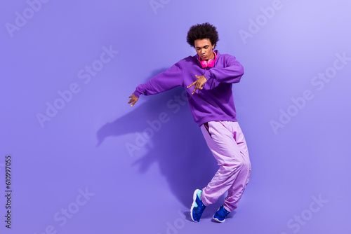 Full size photo of stylish positive person wear violet hoodie pants dancing modern hip hop music isolated on purple color background