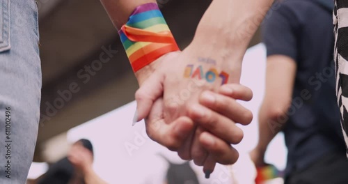 A couple's hands with a rainbow tattoo sticker representing the symbol of homosexuality in a pride parade.