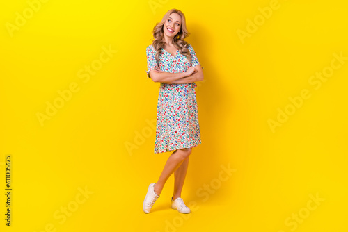 Full length photo of shiny thoughtful woman dressed flower print sarafan arms crossed looking empty space isolated yellow color background