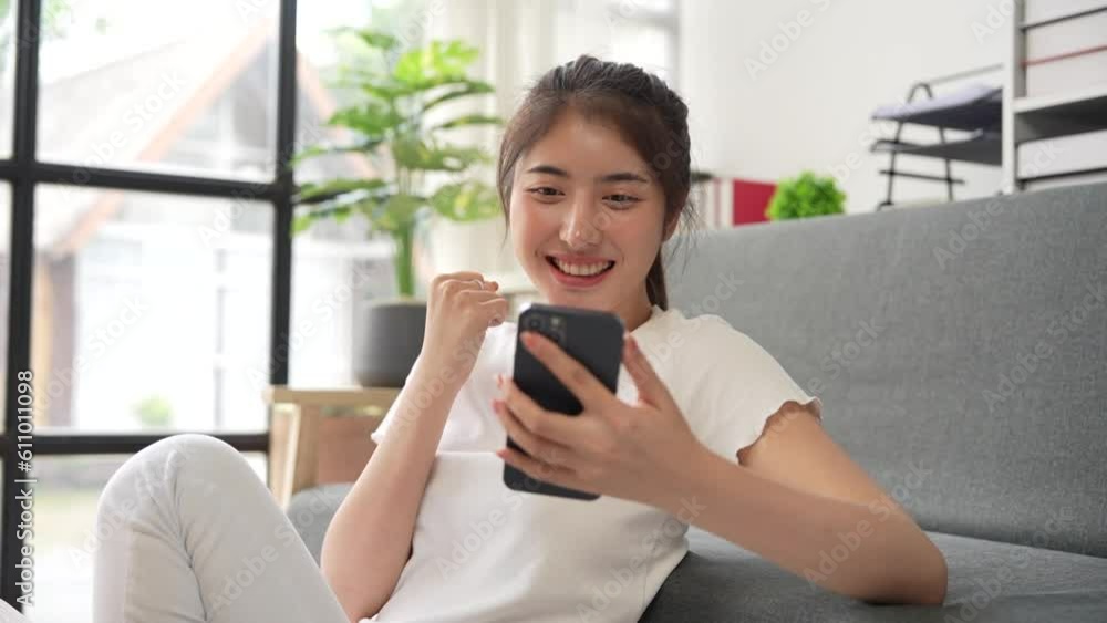 Beautiful asian woman play social media on mobile phone surprised receiving good news. Excited girl holding smartphone sending message feeling happy Beautiful asian woman play social media on mobile phone surprised receiving good news. Excited girl holding smartphone sending message feeling happy